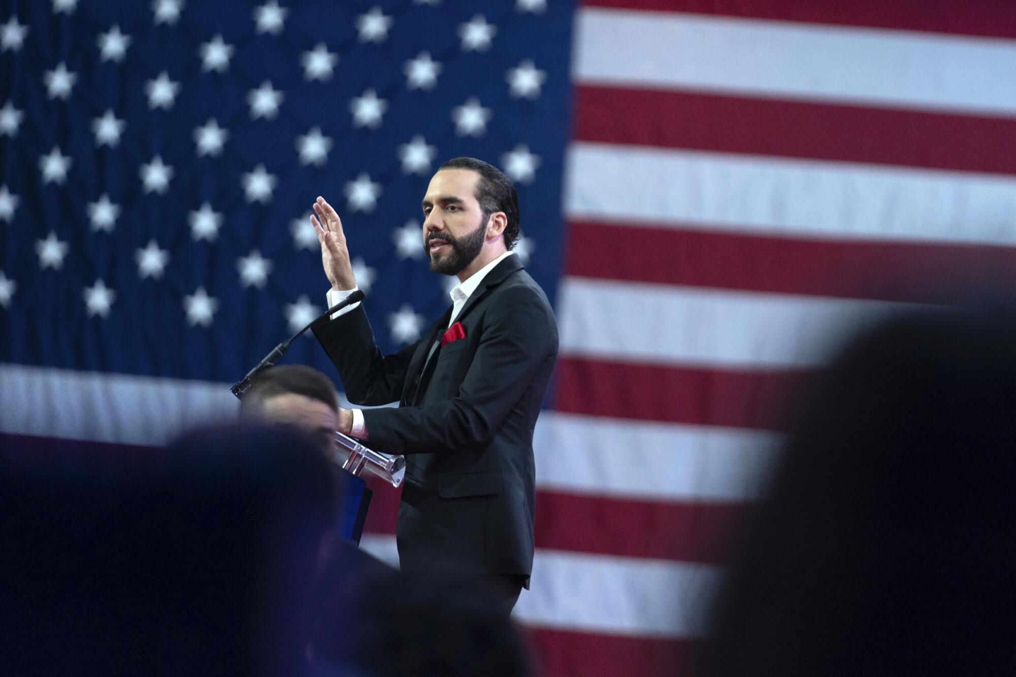 Nayib Bukele speaks in front of an image of a giant U.S. flag.