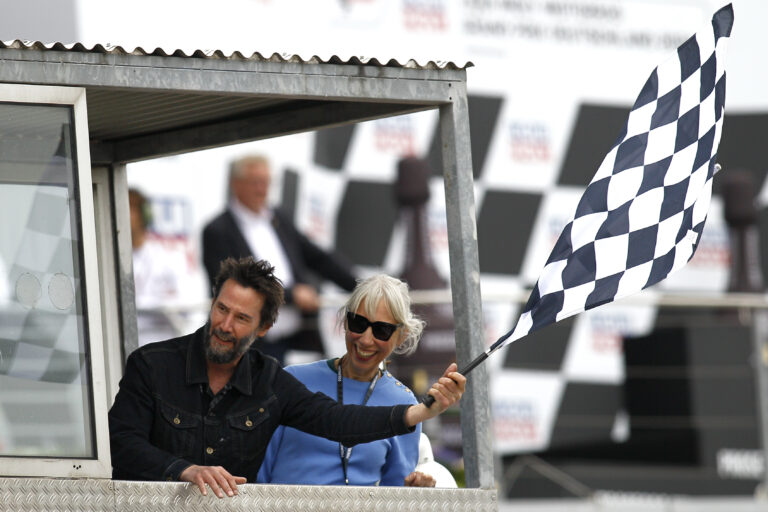 Actor Keanu Reeves waves the chequered flag